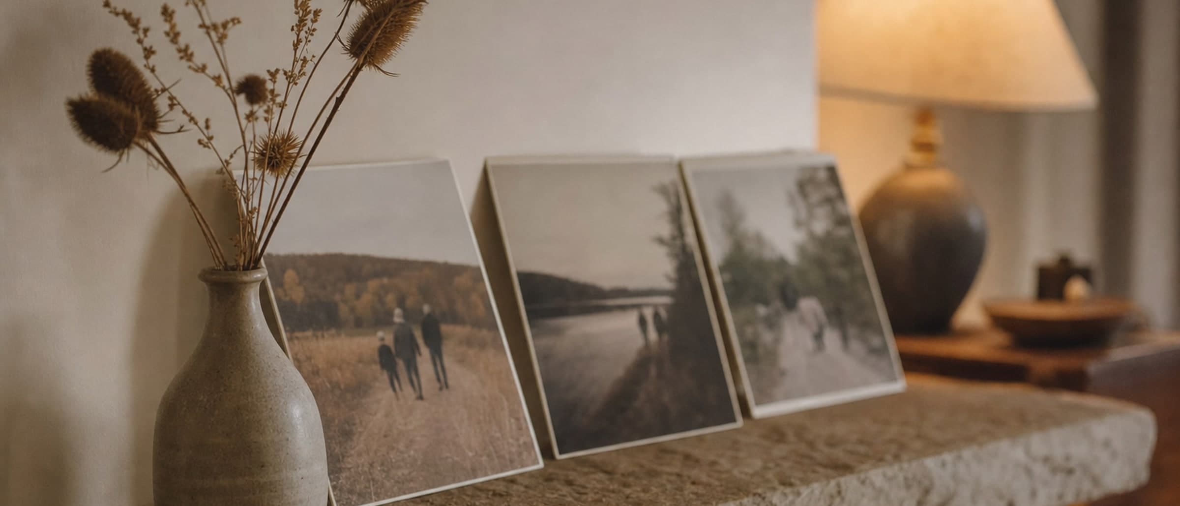 A mantelpiece with family photographs turned slightly away and dried seed heads