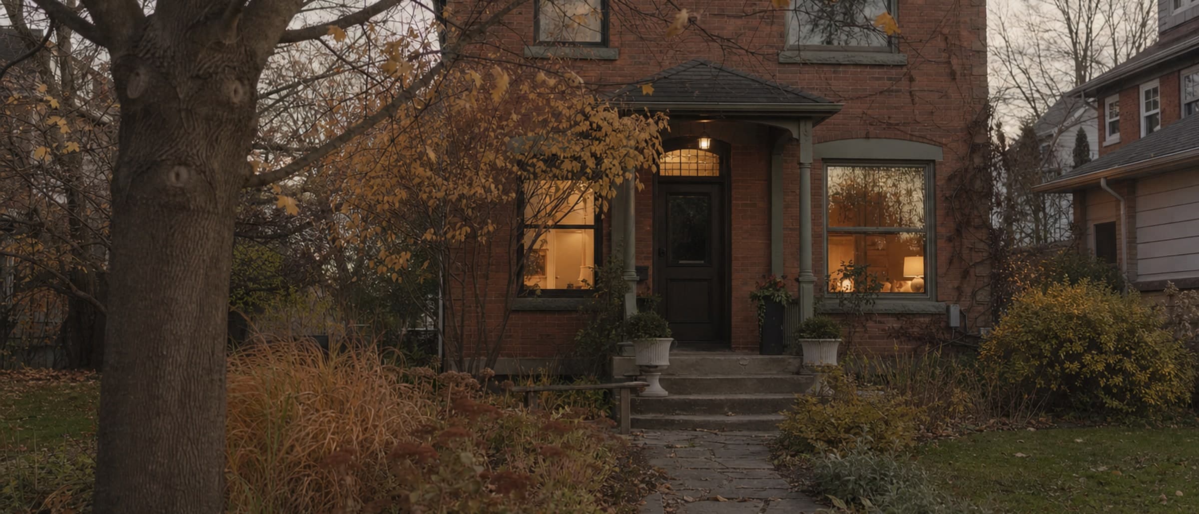 A stone house at dusk with its windows lit from inside